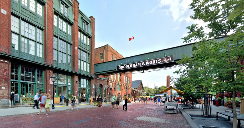 Cobblestone streets of the Distillery District lined with historic brick buildings, shops, and festive lights, reflecting a blend of history and culture